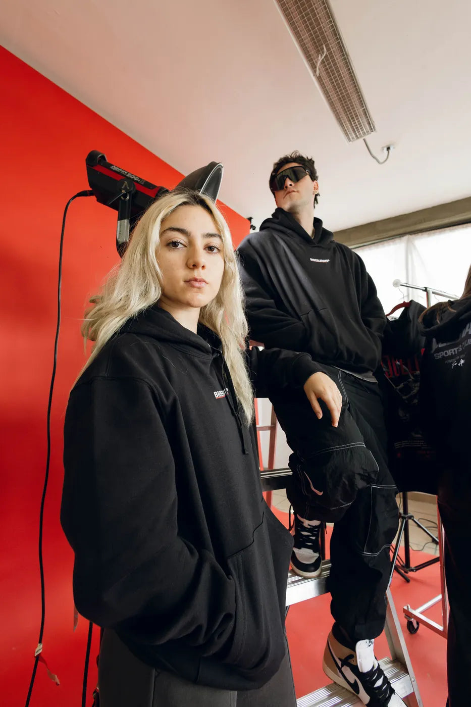 Dos atletas con hoodies negras en un estudio rojo